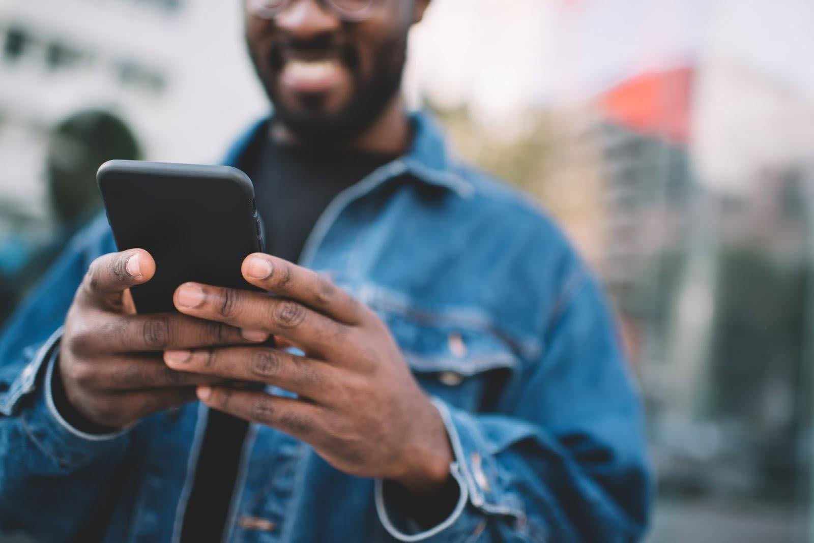 A man holding a cellphone and trying to learn how to find a person by phone number