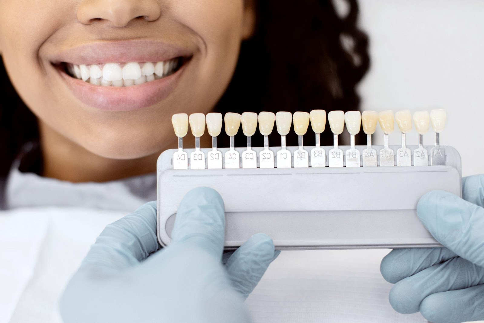 Patient smiling during cosmetic dentistry consultation with dentist holding teeth shade guide for veneers and professional teeth whitening in Bradenton.
